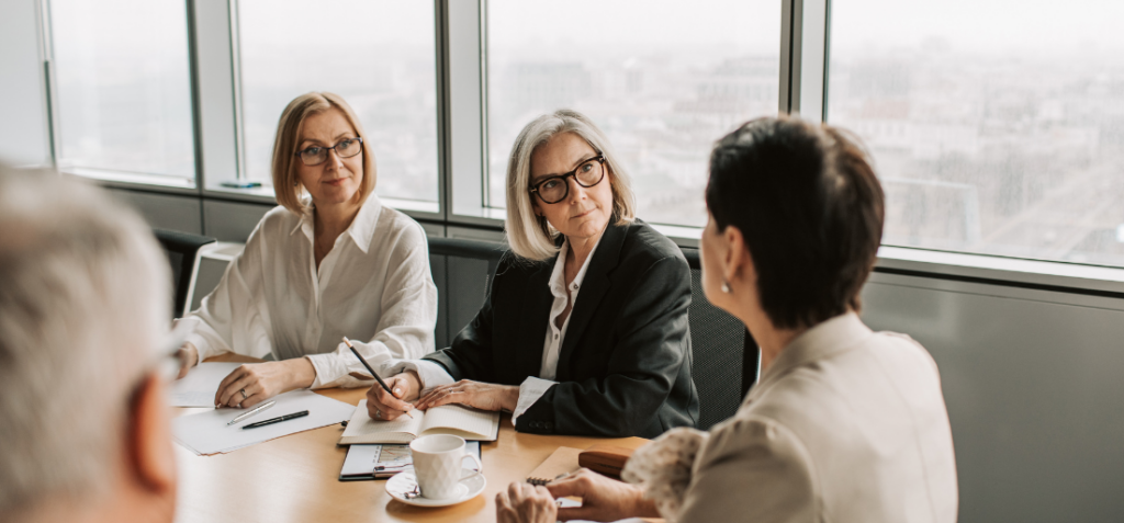 Three women at a boardroom desk.